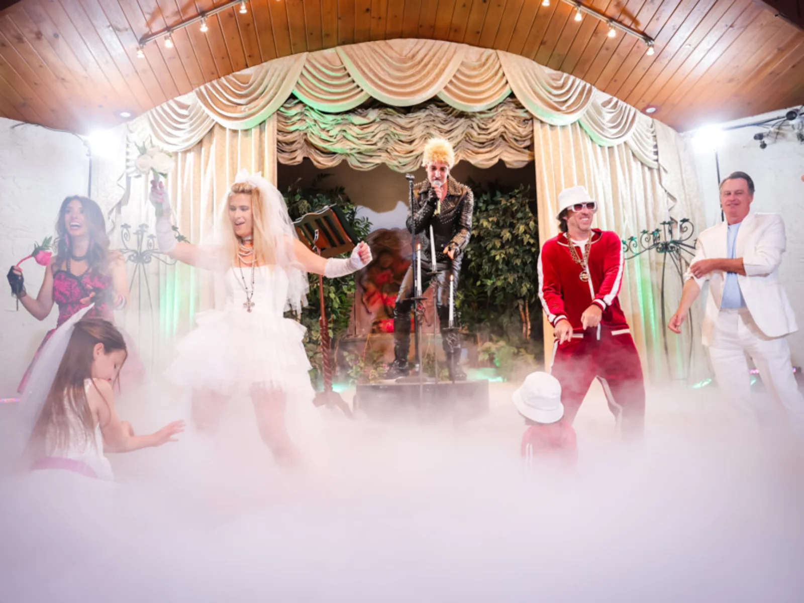 Billy Idol impersonator performing on stage as bride and wedding party dance in stage fog at Viva Las Vegas punk rock themed wedding ceremony
