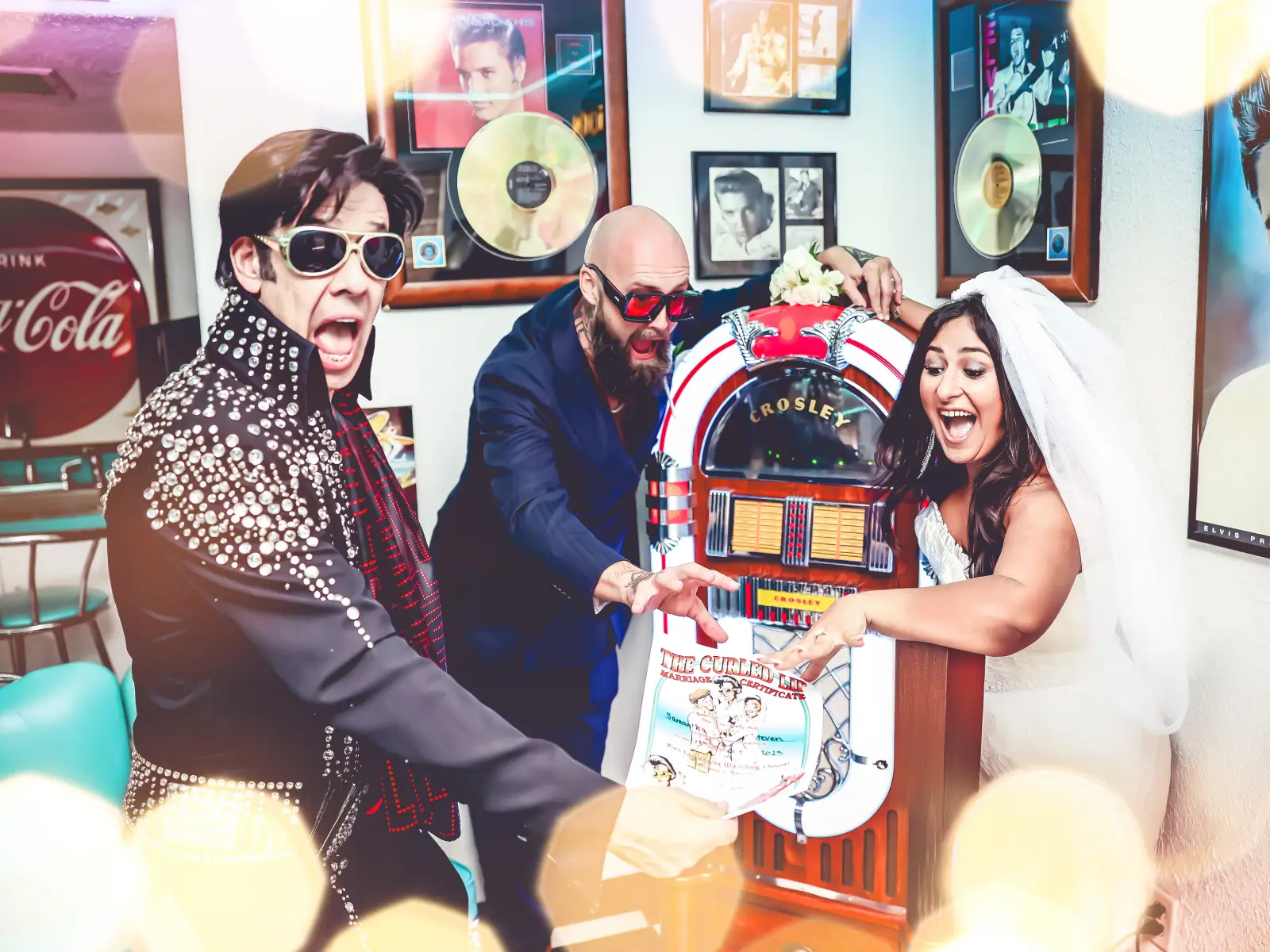 Fun Las Vegas Elvis wedding photo with excited bride and groom celebrating at retro jukebox inside rock-and-roll themed vintage diner chapel
