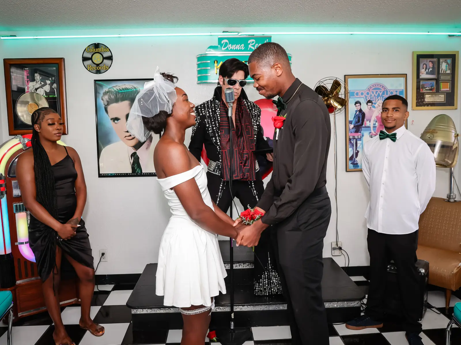 Couple exchanging vows with Elvis officiant and wedding party in retro diner at Las Vegas chapel