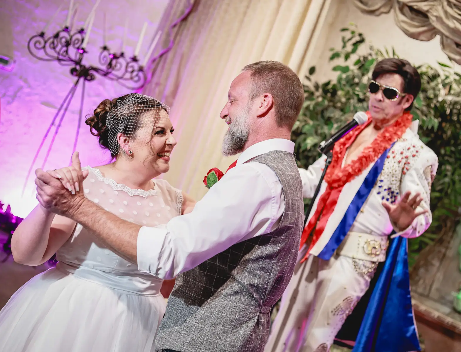 Romantic Las Vegas chapel wedding first dance with smiling bride and groom while Elvis impersonator performs live in elegant ceremony setting