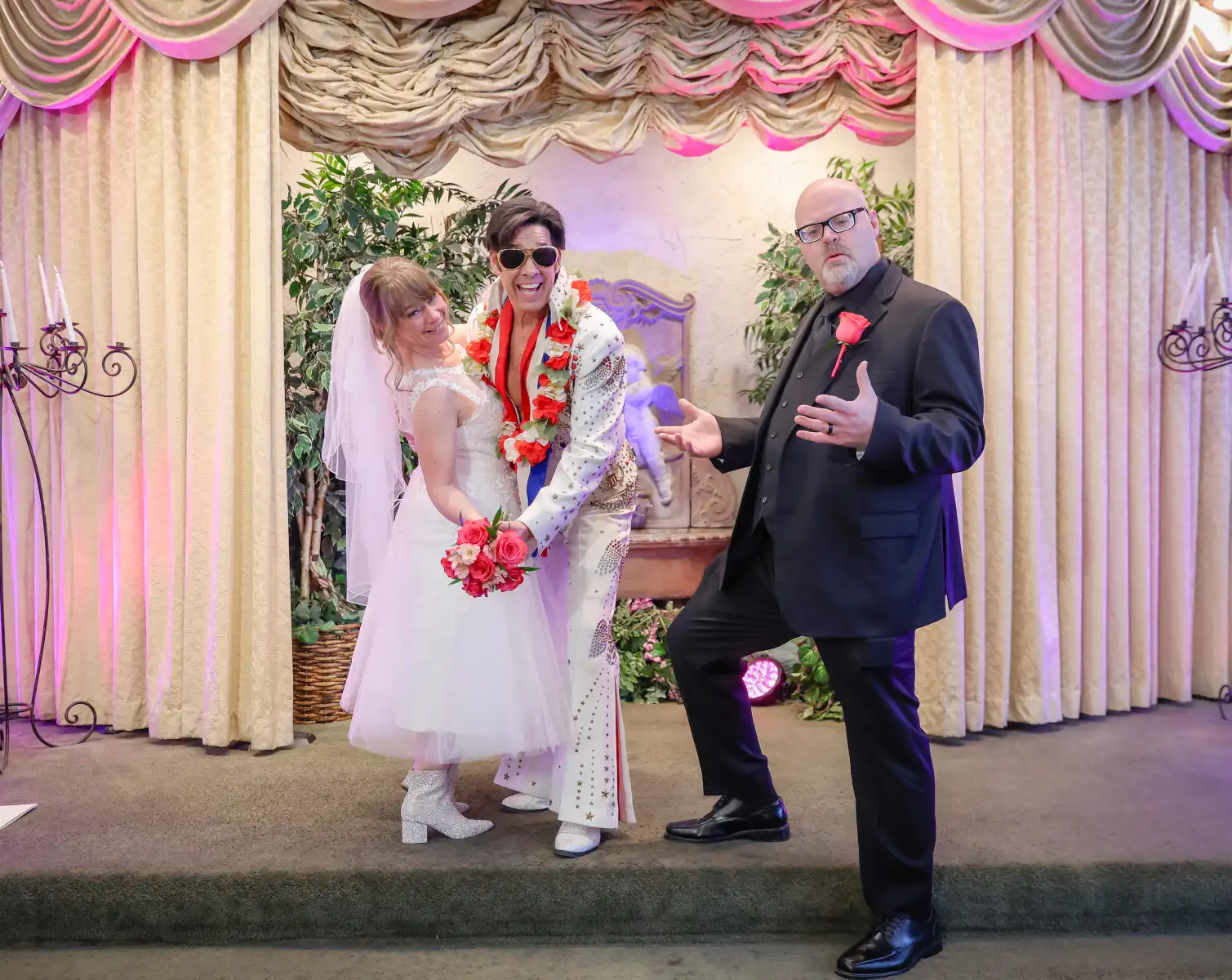 Iconic Las Vegas Elvis wedding photo with bride and groom posing in chapel alongside officiant during fun themed ceremony