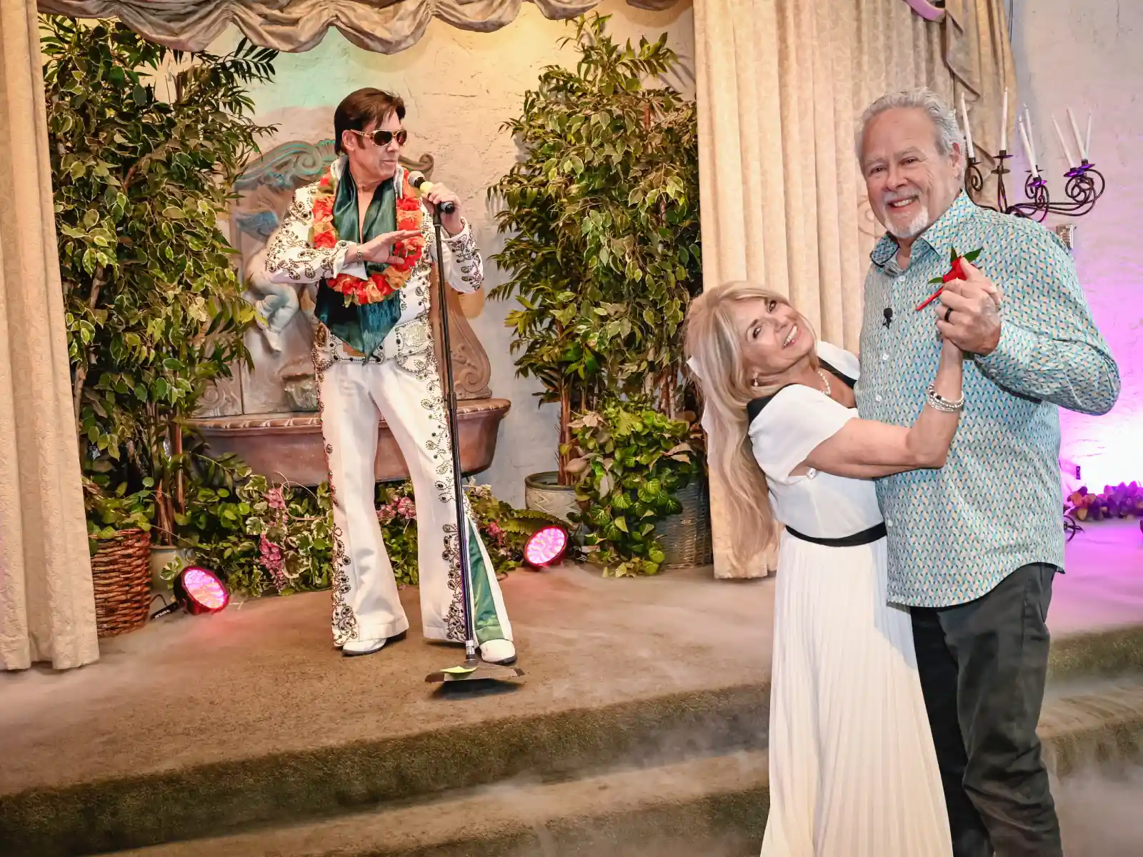 Bride and groom dancing their first dance while an Elvis impersonator serenades them at a Las Vegas wedding chapel