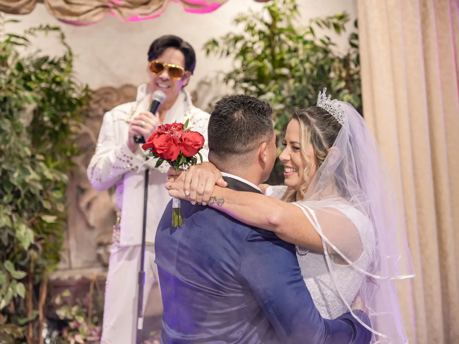 Bride and groom sharing first dance with red rose bouquet during Elvis-officiated Las Vegas chapel wedding