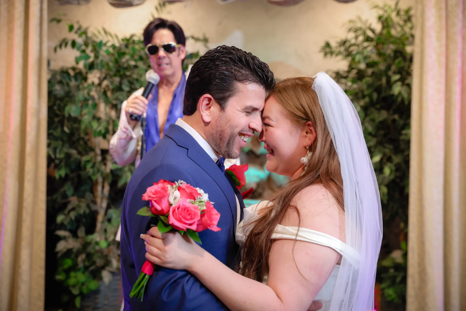 Joyful bride and groom embracing with pink rose bouquet during Elvis-style Las Vegas chapel wedding