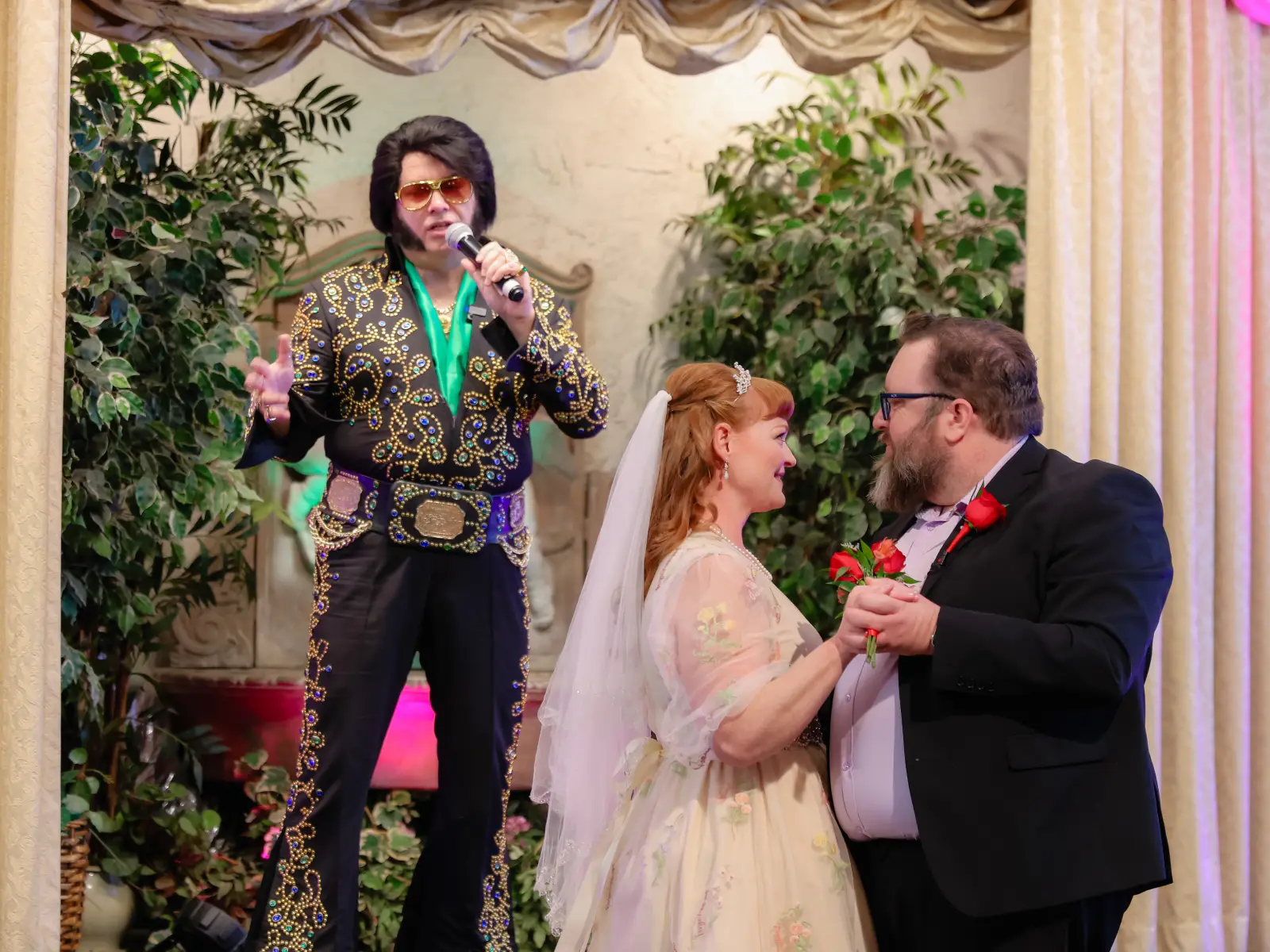 Bride in floral dress and groom in black suit dancing hand-in-hand during Elvis-officiated chapel wedding