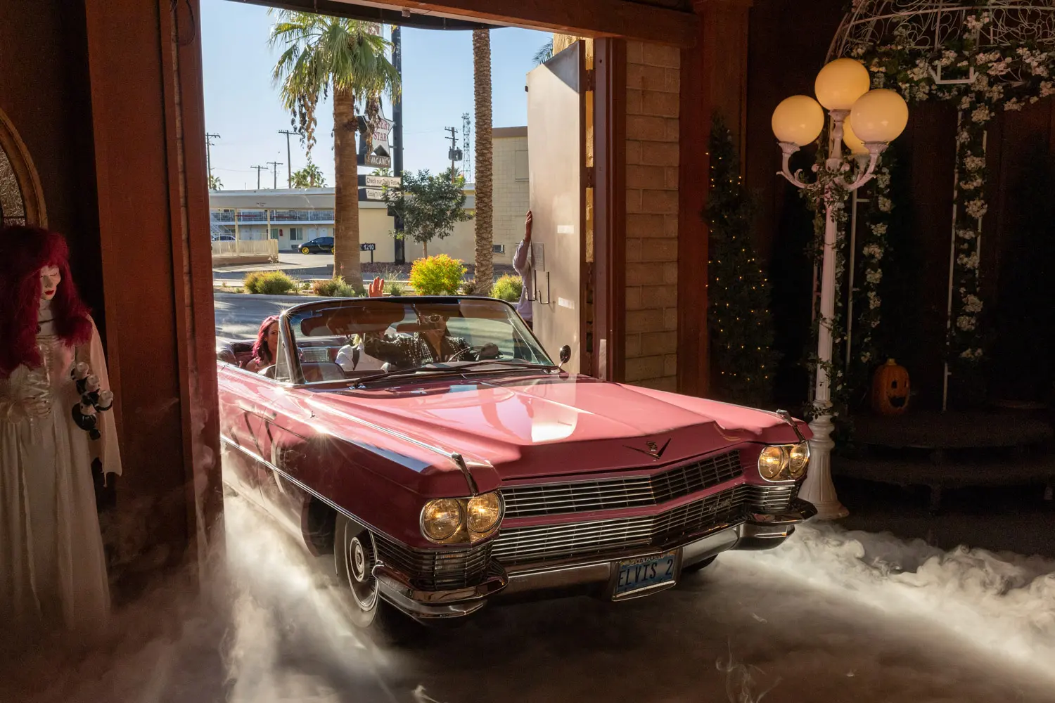 Pink vintage Cadillac convertible driving into wedding chapel entrance with smoke effects and palm trees outside
