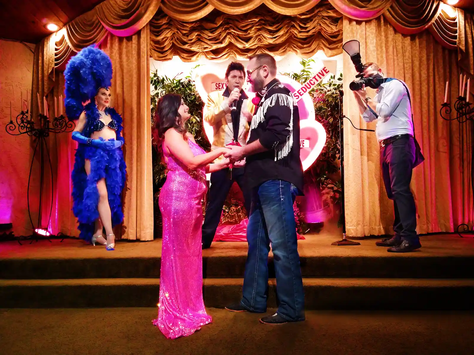 Elvis officiant performing a wedding ceremony with a showgirl attendant and photographer at Viva Las Vegas Wedding Chapel.