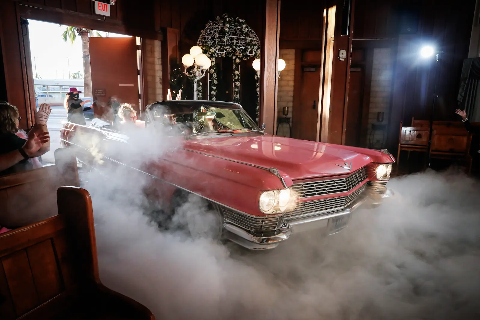 Vintage pink Cadillac convertible making a dramatic entrance with dry ice fog at Viva Las Vegas Wedding Chapel.