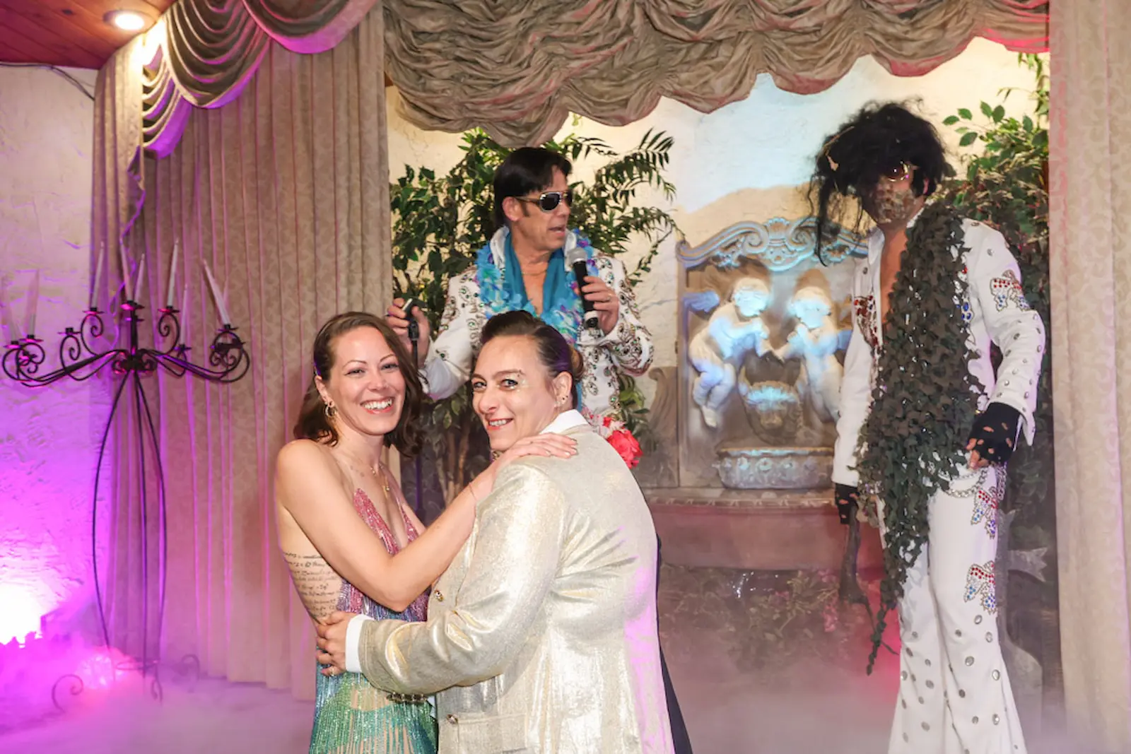 Same-sex couple celebrating with Elvis and zombie Elvis impersonators at themed wedding at Viva Las Vegas Wedding Chape