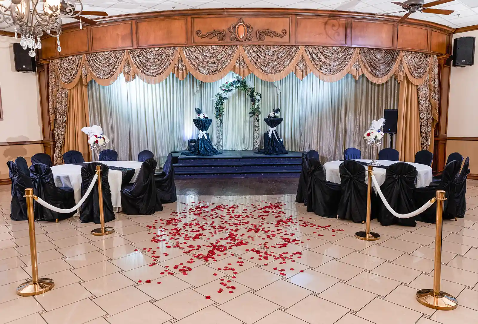 Vegas Event Center wedding ceremony setup with rose petal aisle, floral arch, and gold stanchions