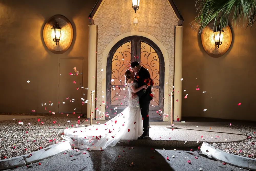 Couple kissing with rose petals falling at the entrance of the Las Vegas Event Center at night