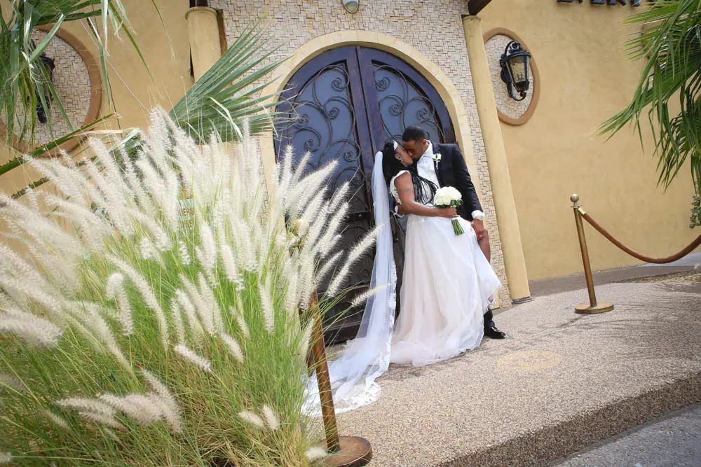 Newlywed couple kissing outside the wrought iron doors of the Las Vegas Event Center