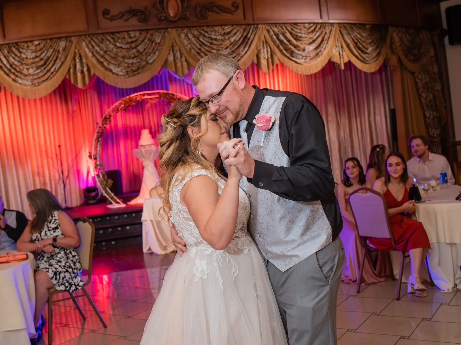 Bride and groom sharing first dance while guests watch with pink stage lighting at Vegas Event Center