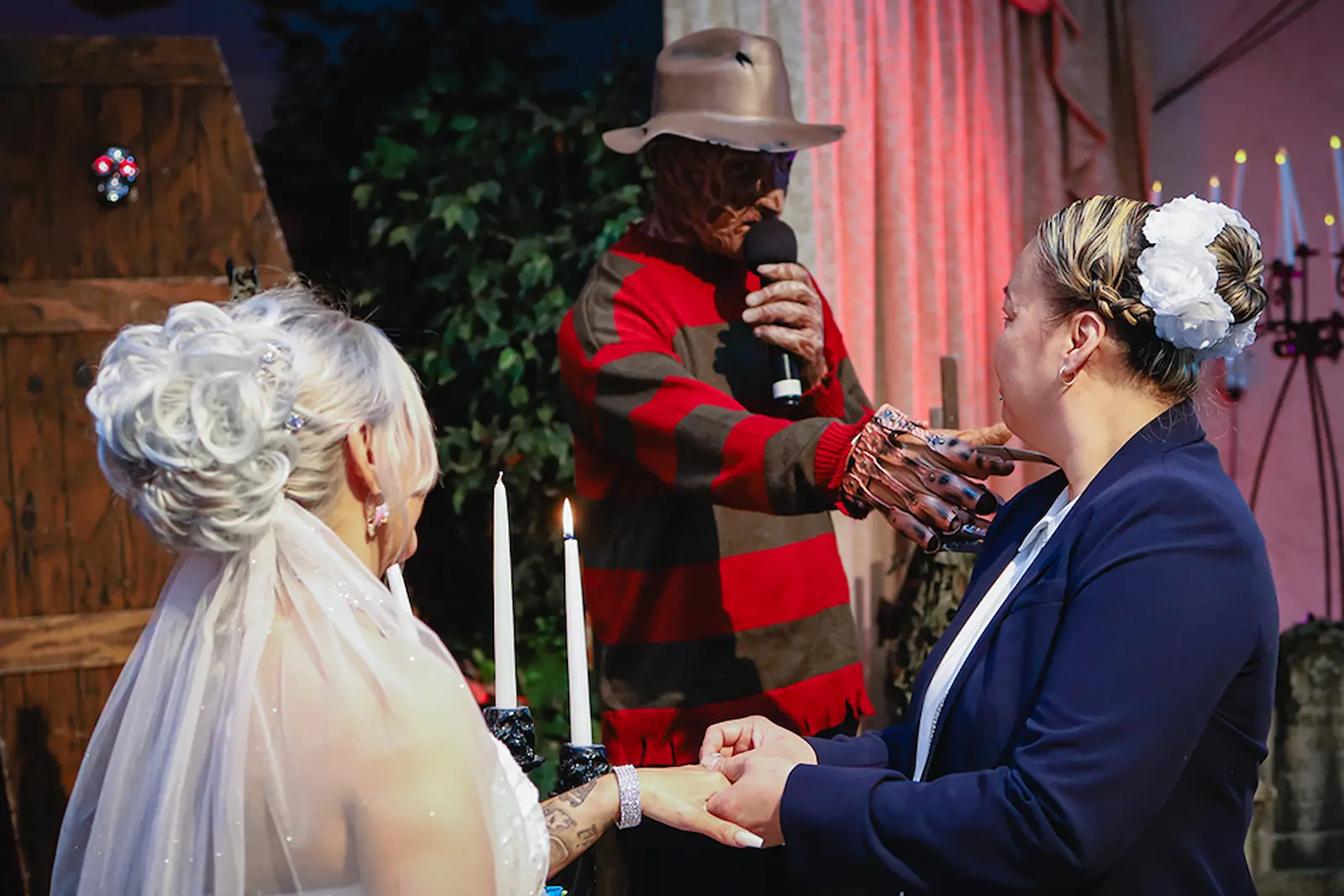Freddy Krueger officiating a same-sex wedding ceremony beside lit candles at a Las Vegas horror chapel