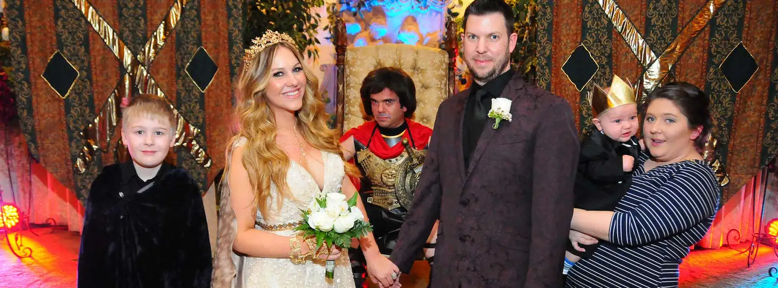 Family celebrating a medieval gladiator-themed wedding at a Las Vegas chapel with gold accents, Roman gladiator officiant, and royal costumes