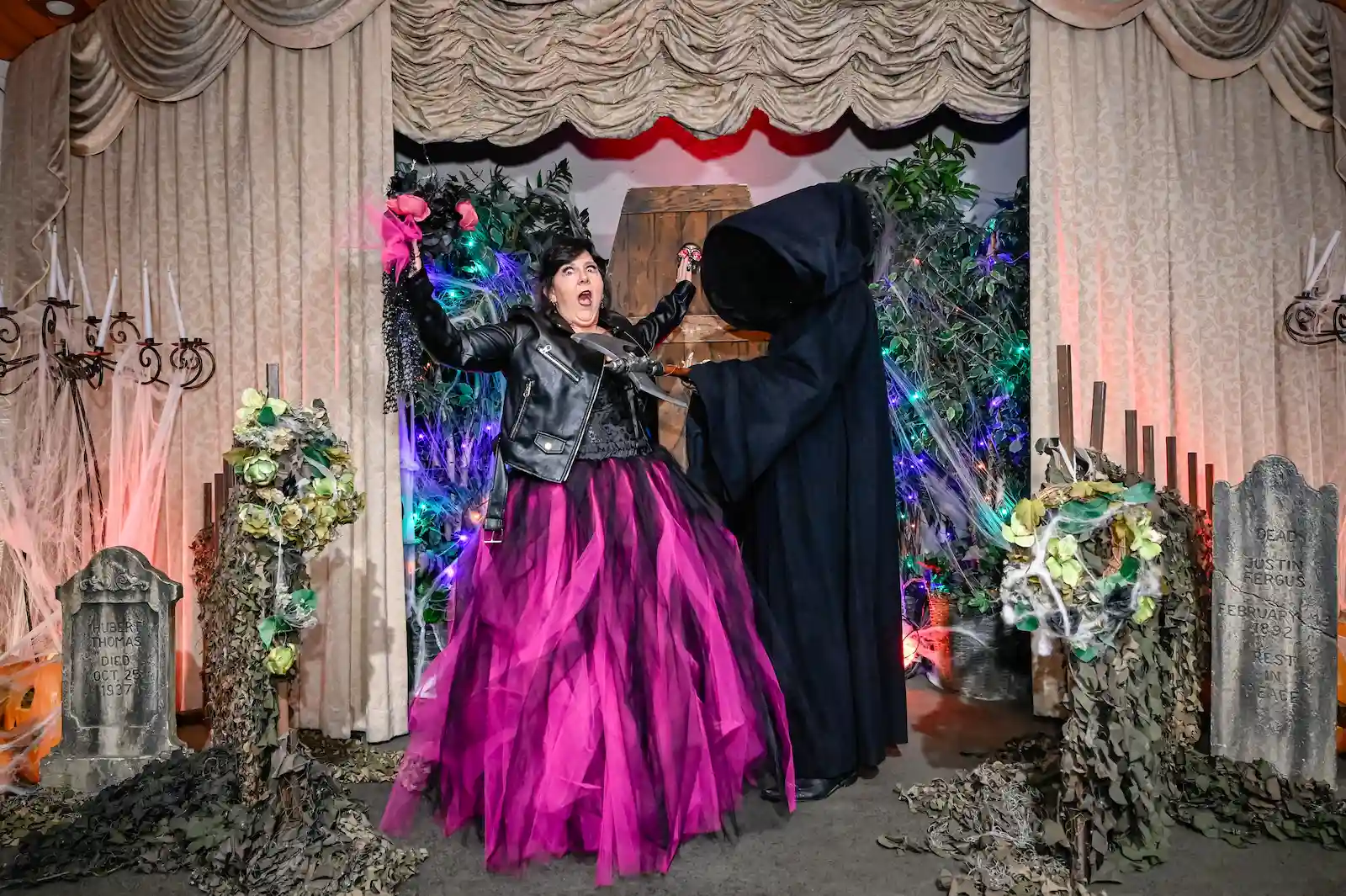 Bride in a pink tulle skirt screaming playfully as a Grim Reaper grabs her at a Las Vegas halloween wedding.