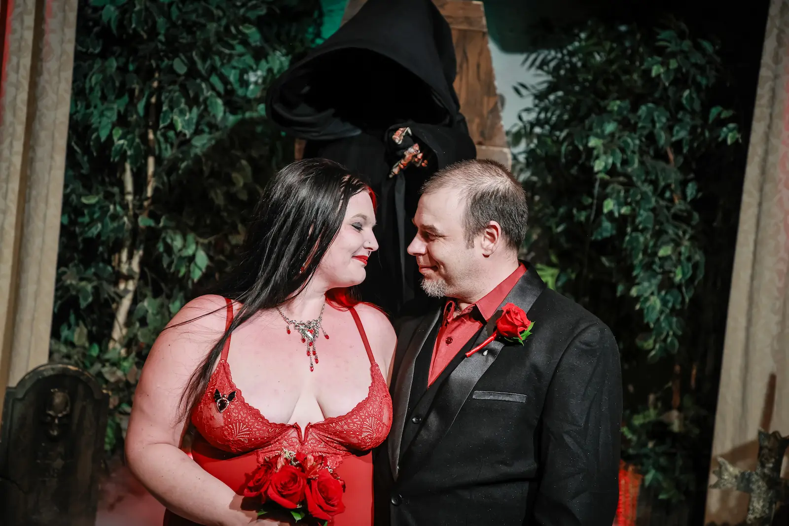 Bride in a red lace dress and groom in a black tuxedo gazing at each other at a Las Vegas gothic wedding.