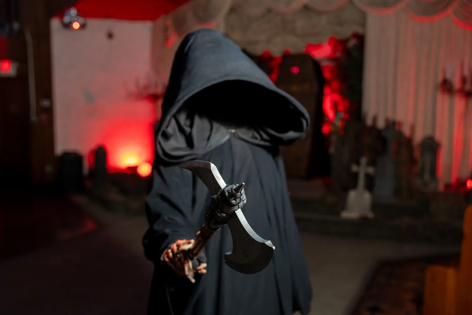 Grim Reaper character holding an axe in a red-lit gothic Las Vegas wedding chapel with tombstones in the background