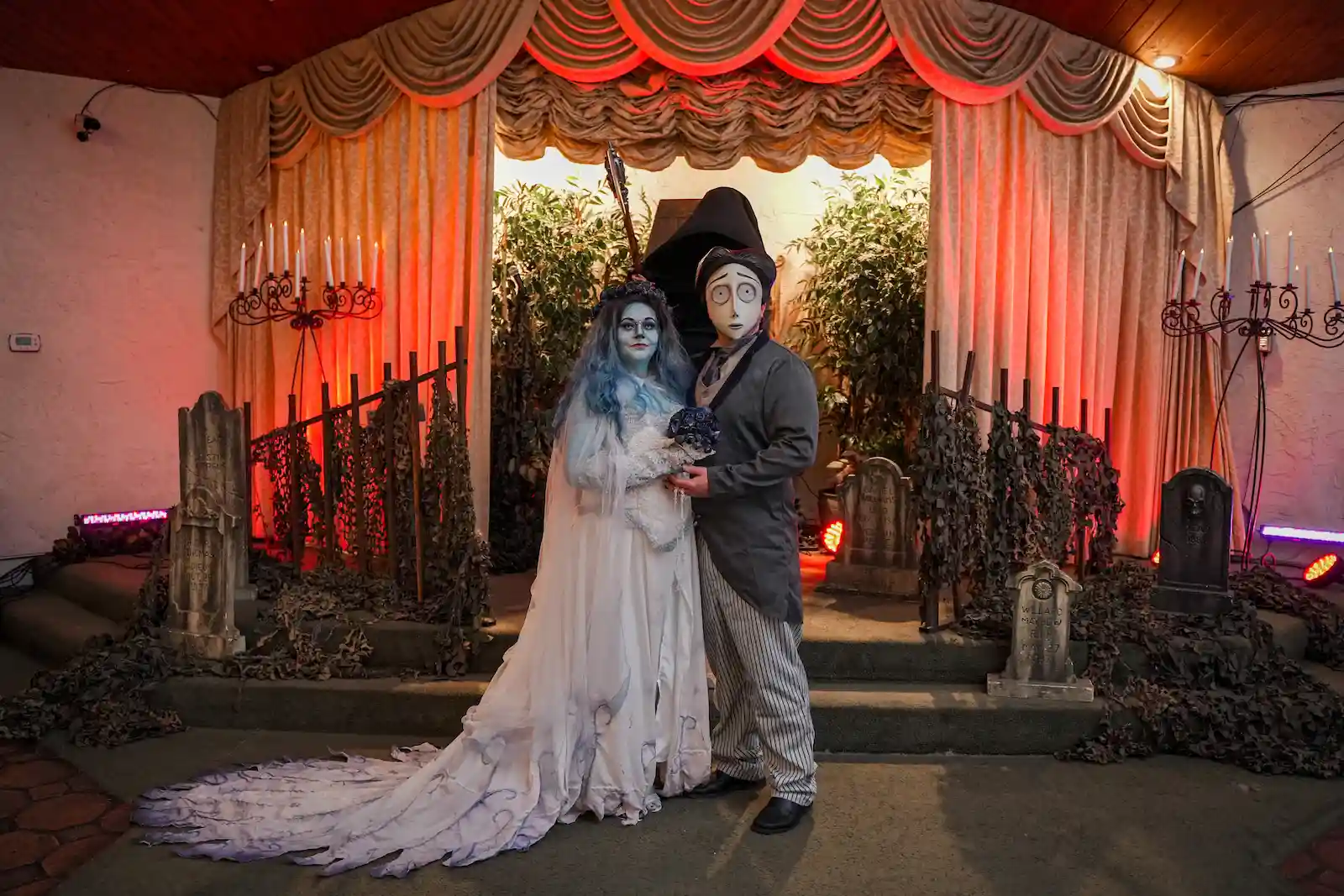 Couple in full Corpse Bride and Victor Van Dort costumes and makeup posing at a Las Vegas gothic graveyard wedding venue