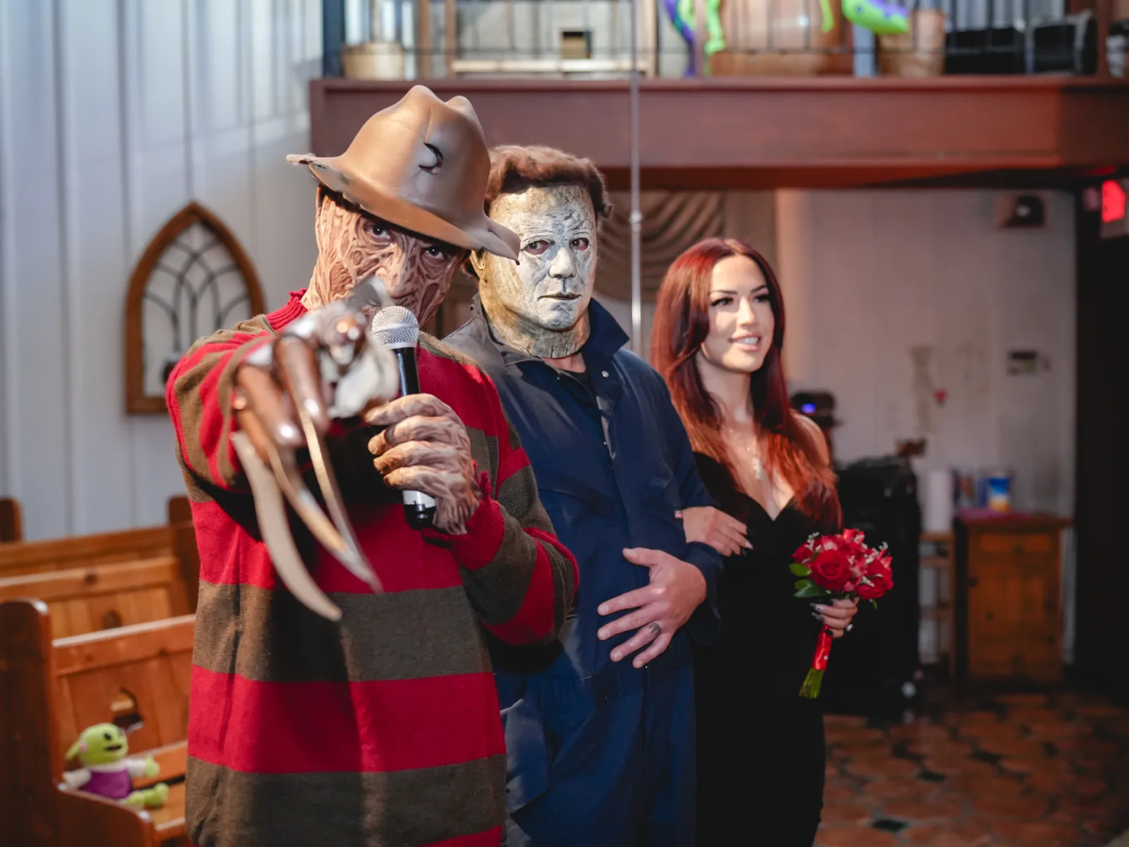 Freddy Krueger pointing razor claws at the camera with Michael Myers and a bride holding red roses at a Las Vegas wedding chapel