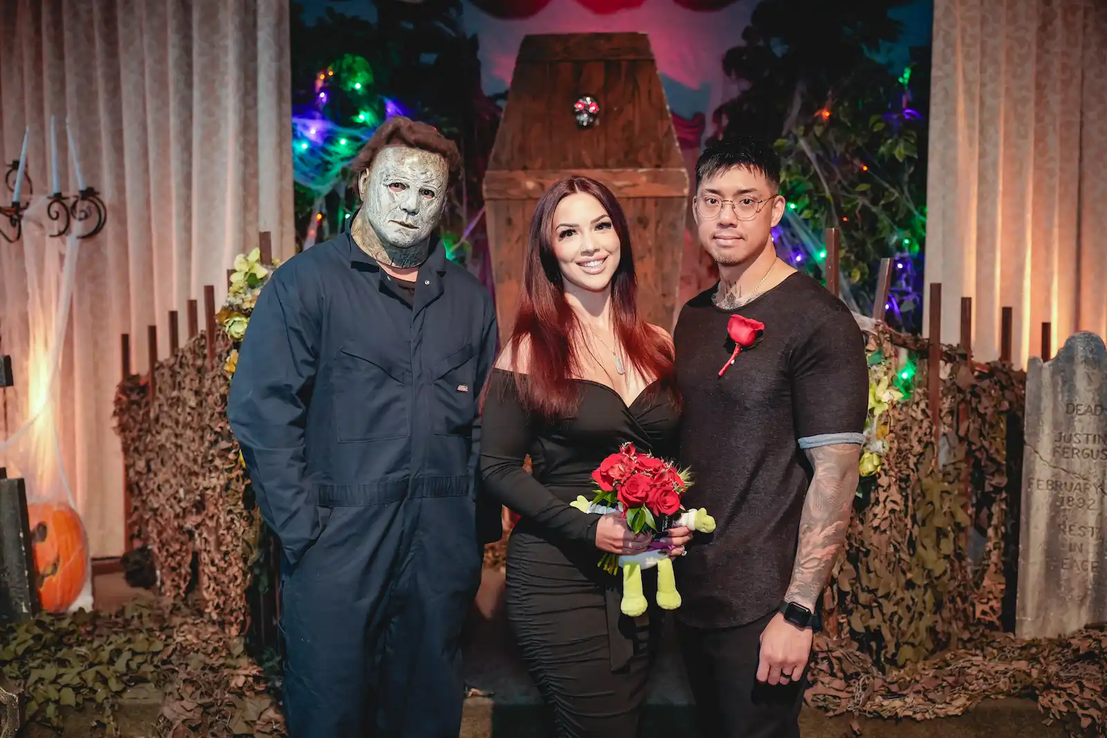 Couple posing with Michael Myers character in front of a Halloween coffin backdrop at a Las Vegas horror wedding.