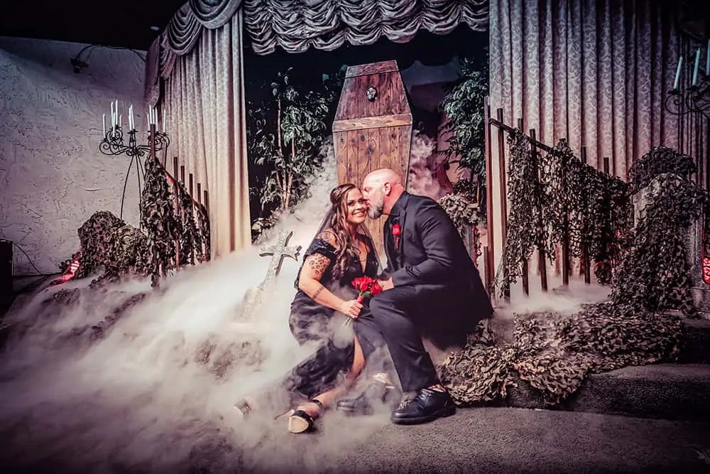 Gothic couple in black posing with coffin and fog on spooky stage at Las Vegas chapel