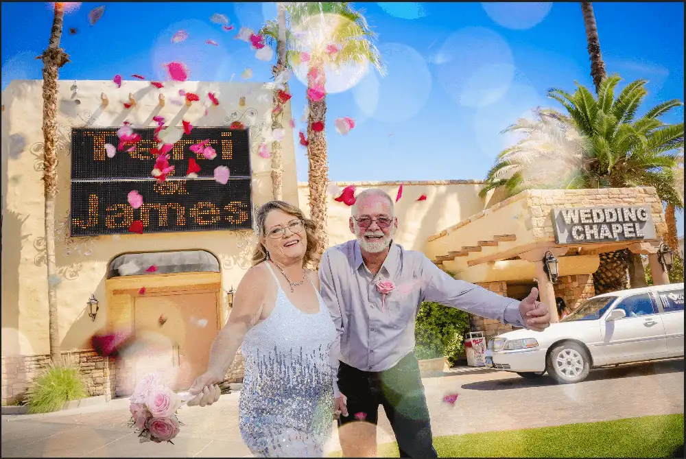 Rose petals falling on happy couple outside Las Vegas wedding chapel with marquee sign