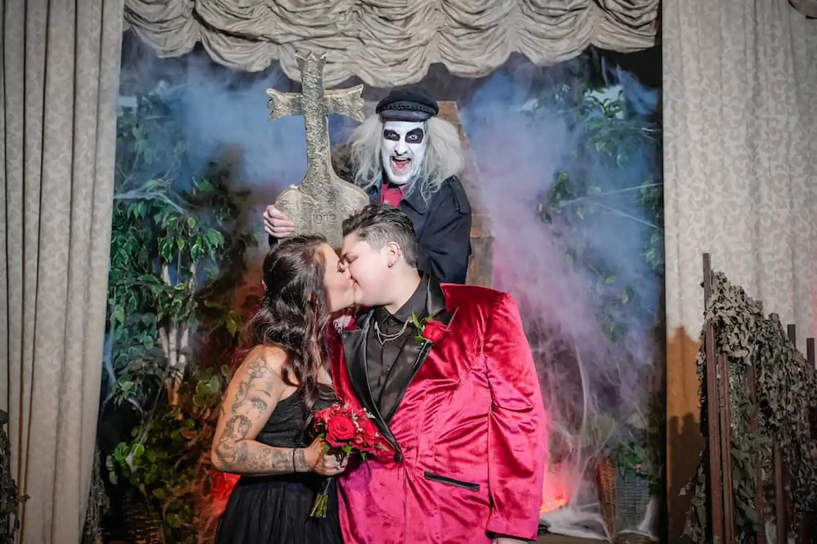 Couple kissing in front of gothic cross with Beetlejuice impersonator and stage fog at a Las Vegas wedding chapel