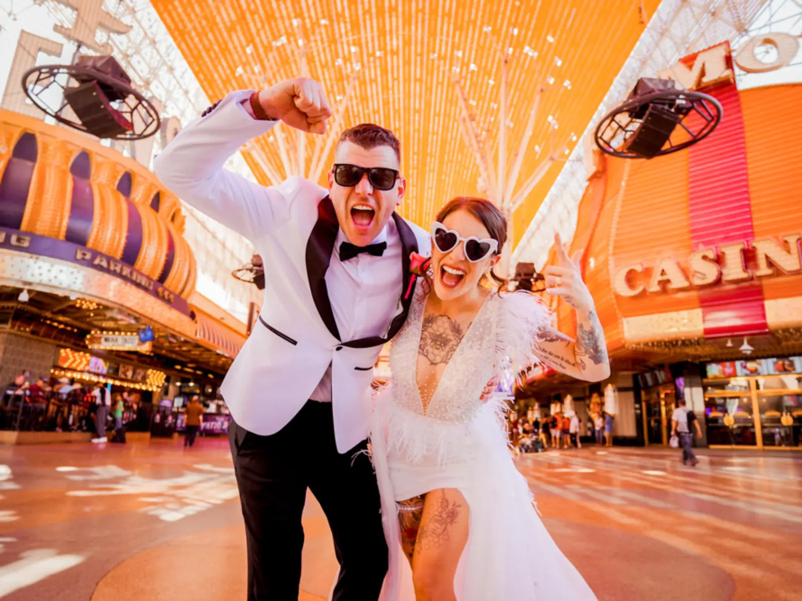 Newlywed couple celebrating under Fremont Street lights and casino signs in Las Vegas