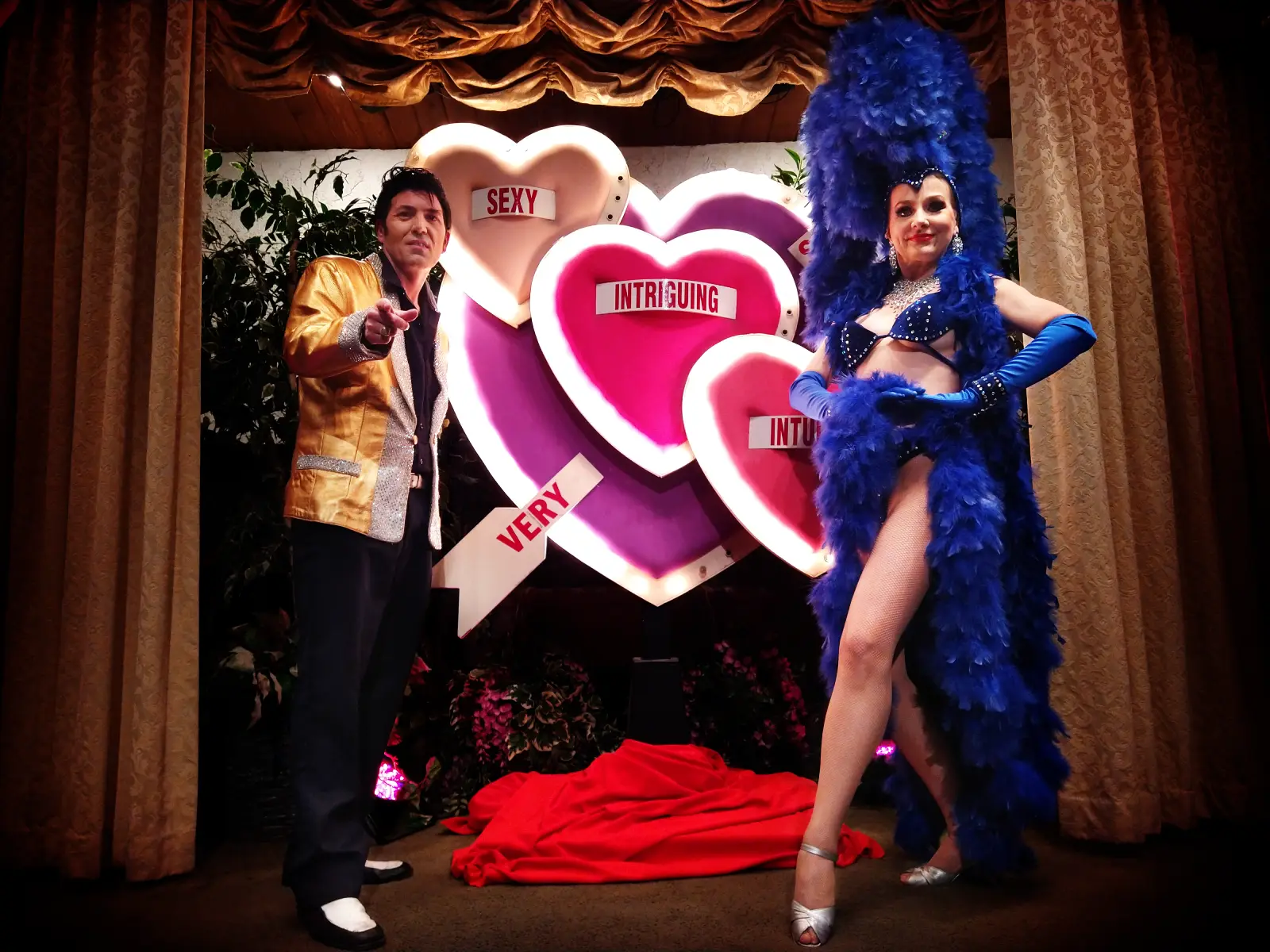 Elvis impersonator and Las Vegas showgirl posing by glowing heart signs