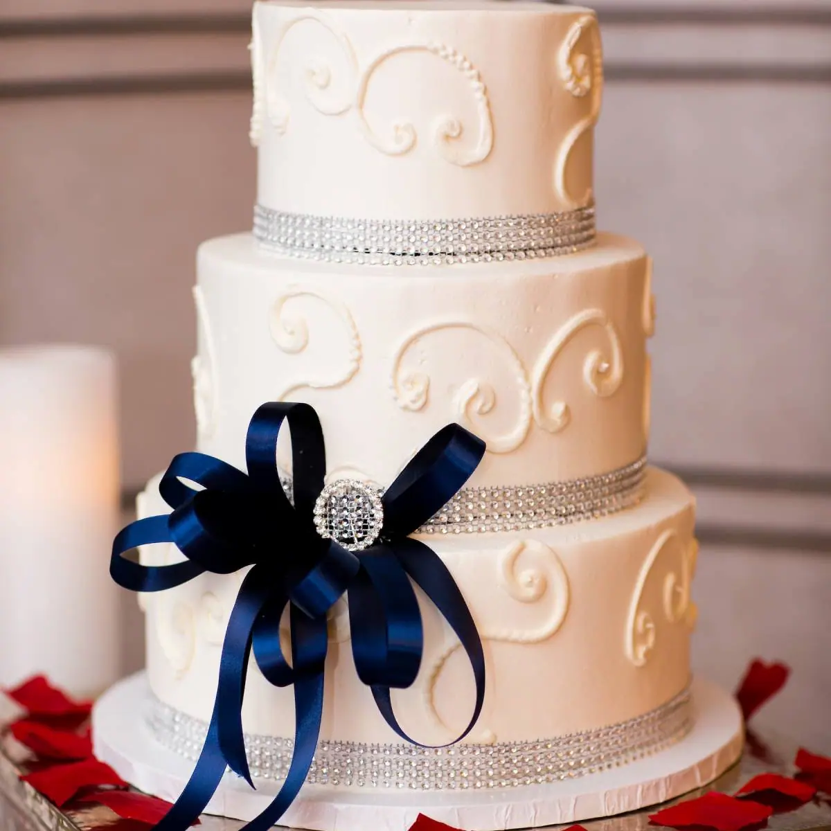 Elegant three-tier wedding cake with navy ribbon and rhinestone brooch at Viva Las Vegas Weddings
