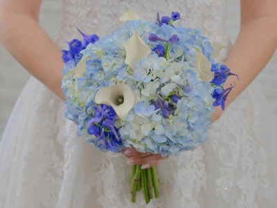 Blue hydrangea bouquet accented with white calla lilies and irises