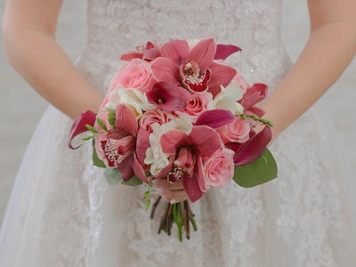 Lush pink orchids and roses arranged in a romantic wedding bouquet