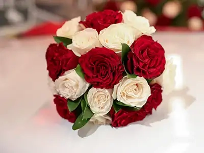 Classic wedding bouquet of red and white roses resting on a white surface