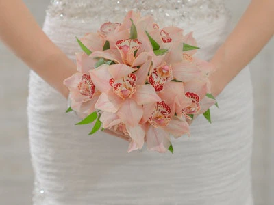 Delicate bouquet of pale pink cymbidium orchids with green leaf accents