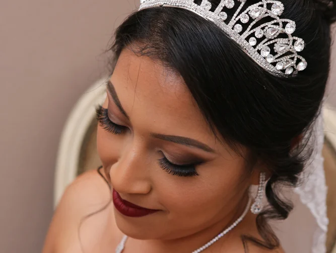 Bride wearing crystal tiara, lashes, and berry lips