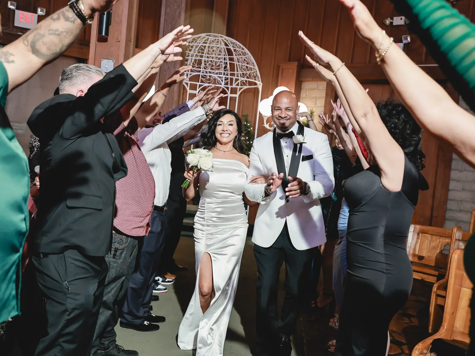 Bride and groom walking through a tunnel of raised hands during their wedding recessional at a Las Vegas chapel.