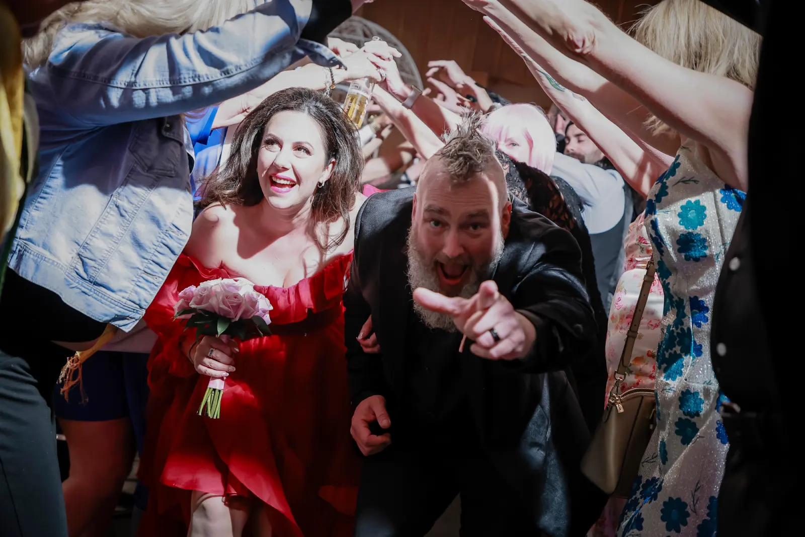 Bride in a red dress and groom celebrating with guests during a Las Vegas wedding chapel recessional
