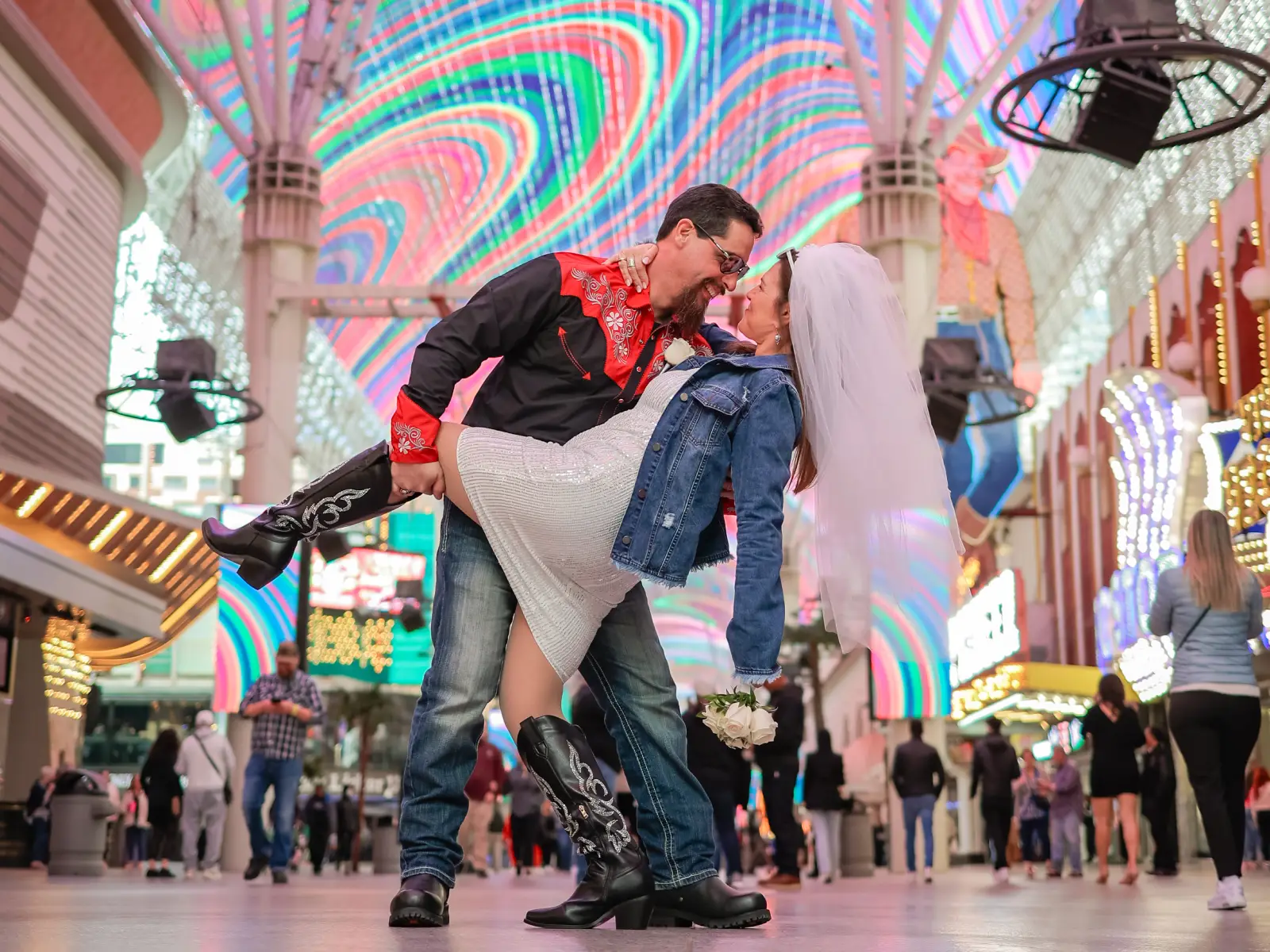 Groom dipping bride in cowboy boots under the colorful LED canopy at Fremont Street Experience Las Vegas wedding photoshoot