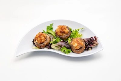 Sausage stuffed mushrooms served on a white plate with mixed greens