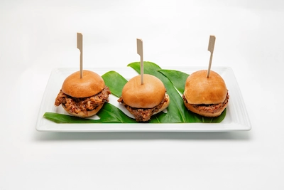 Three cheeseburger sliders on brioche buns served on a bed of spinach