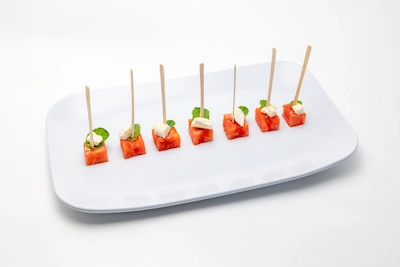 Watermelon feta basil bites on skewers arranged on a white plate