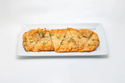 Golden three cheese flatbread topped with fresh herbs on a white plate