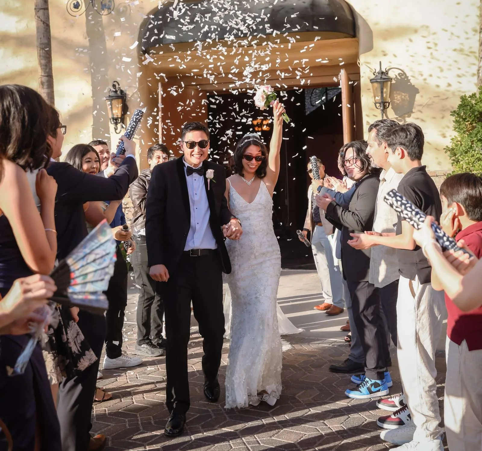 Newlyweds exit through a shower of confetti as guests cheer at their Vegas wedding celebration