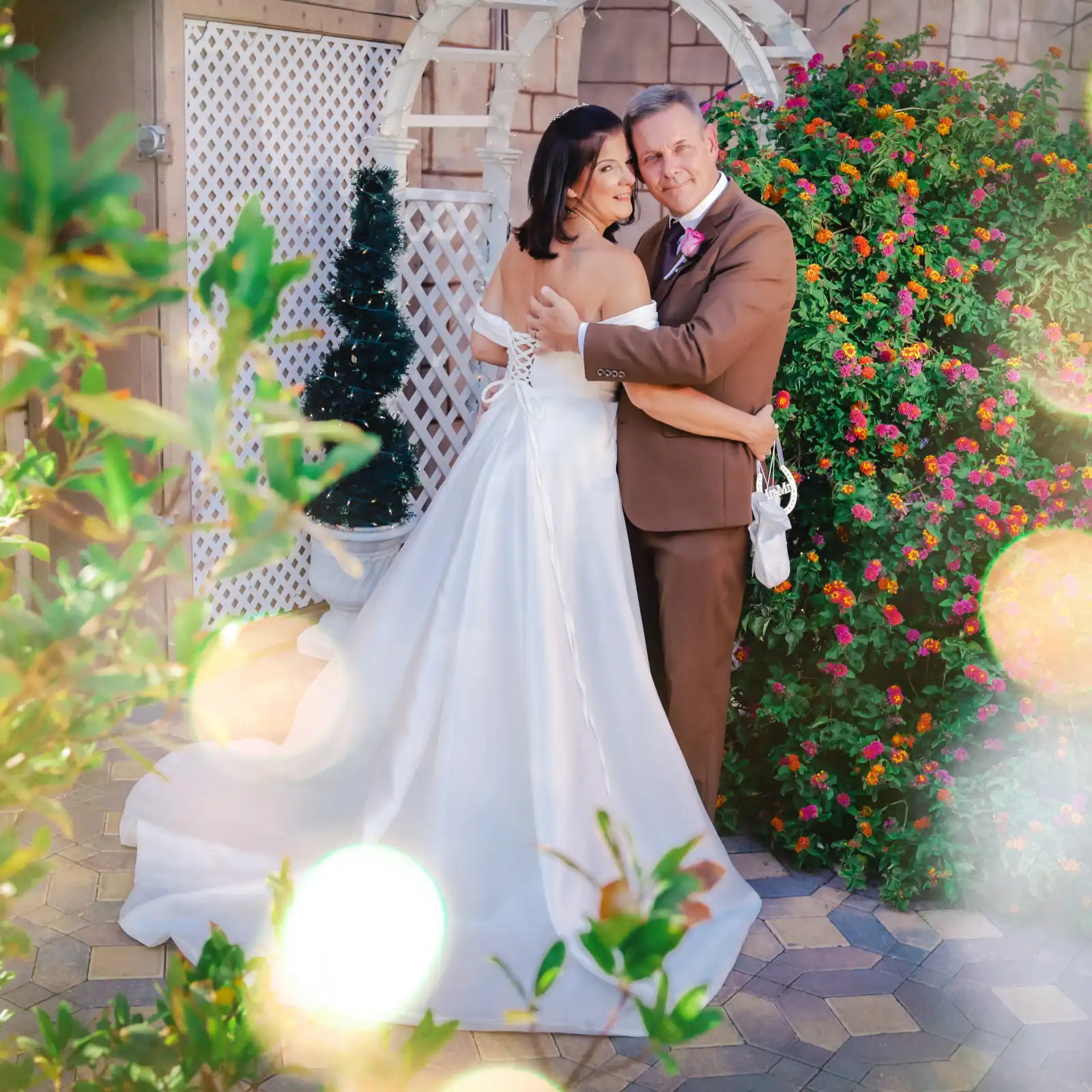 bride and groom embracing in a garden setting with colorful flowers in the background