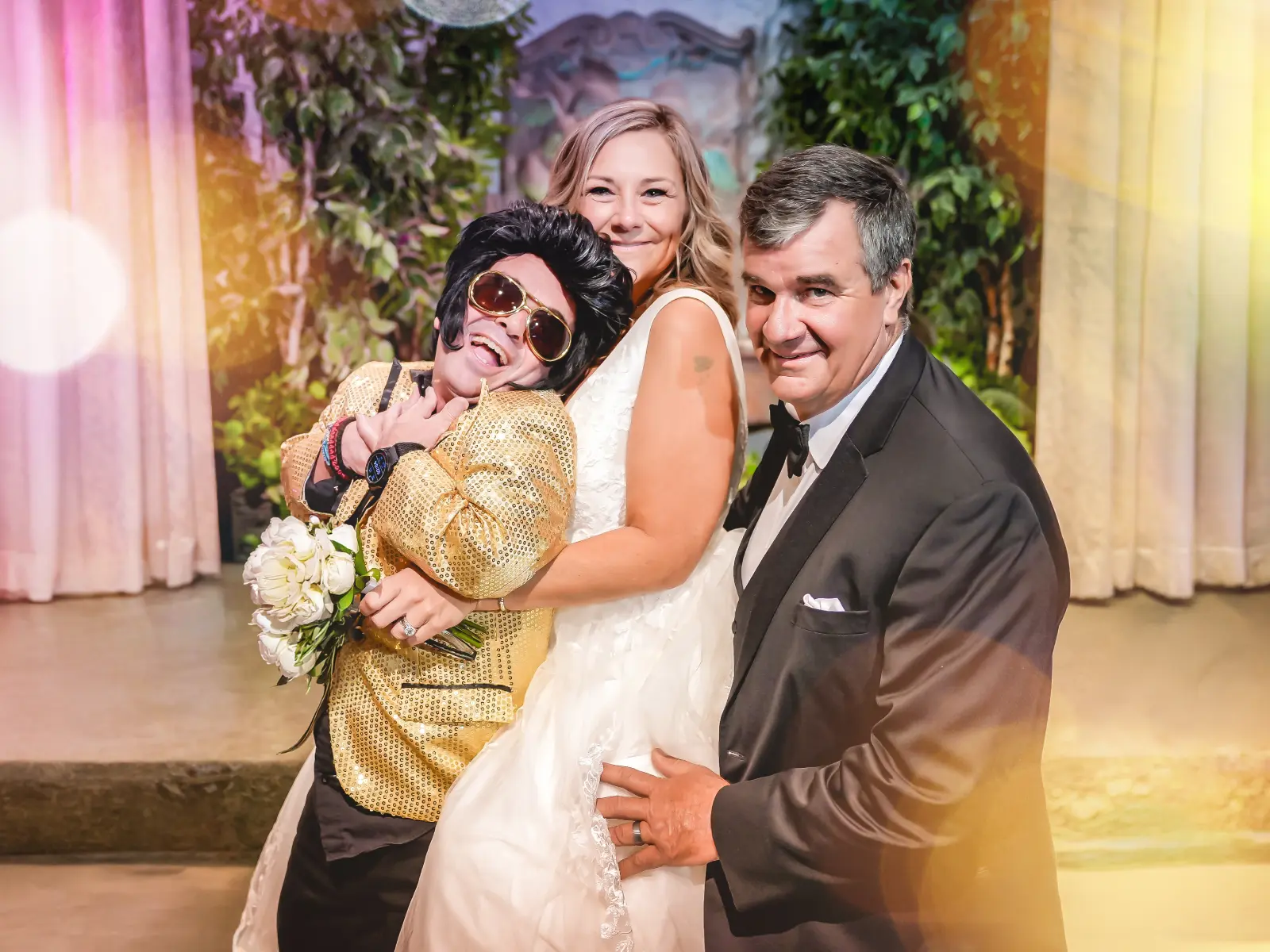 Fun Las Vegas Elvis wedding photo with playful couple posing alongside Elvis impersonator in elegant chapel surrounded by romantic decor