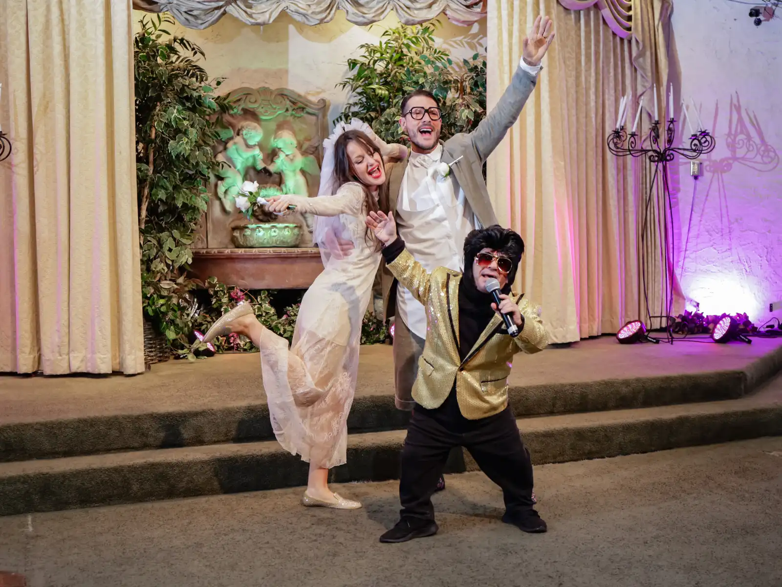 Fun Las Vegas Elvis wedding celebration with bride and groom posing energetically alongside Elvis impersonator during lively chapel performance