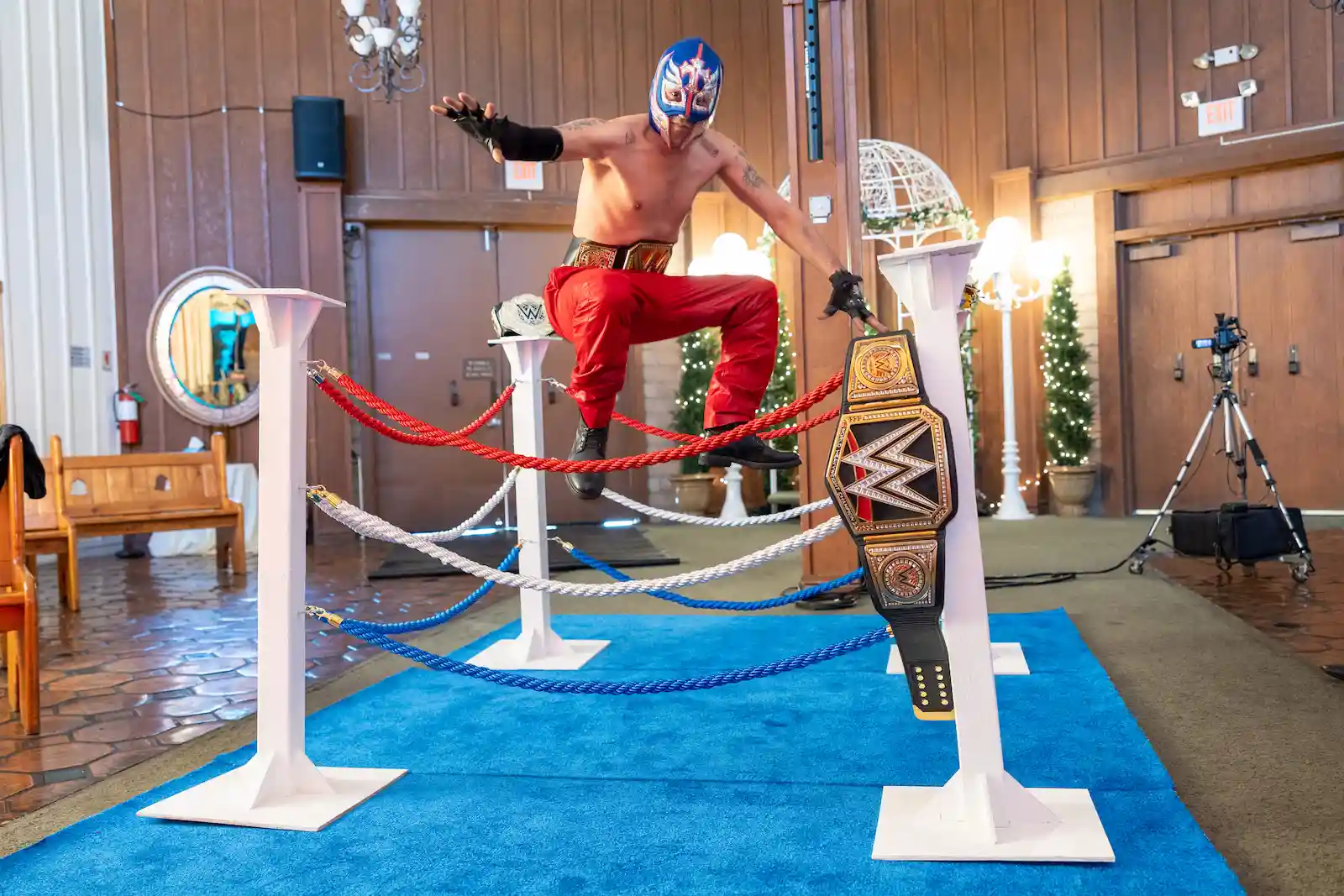 Lucha libre wrestler posing between ropes in mini wrestling ring with WWE championship belts