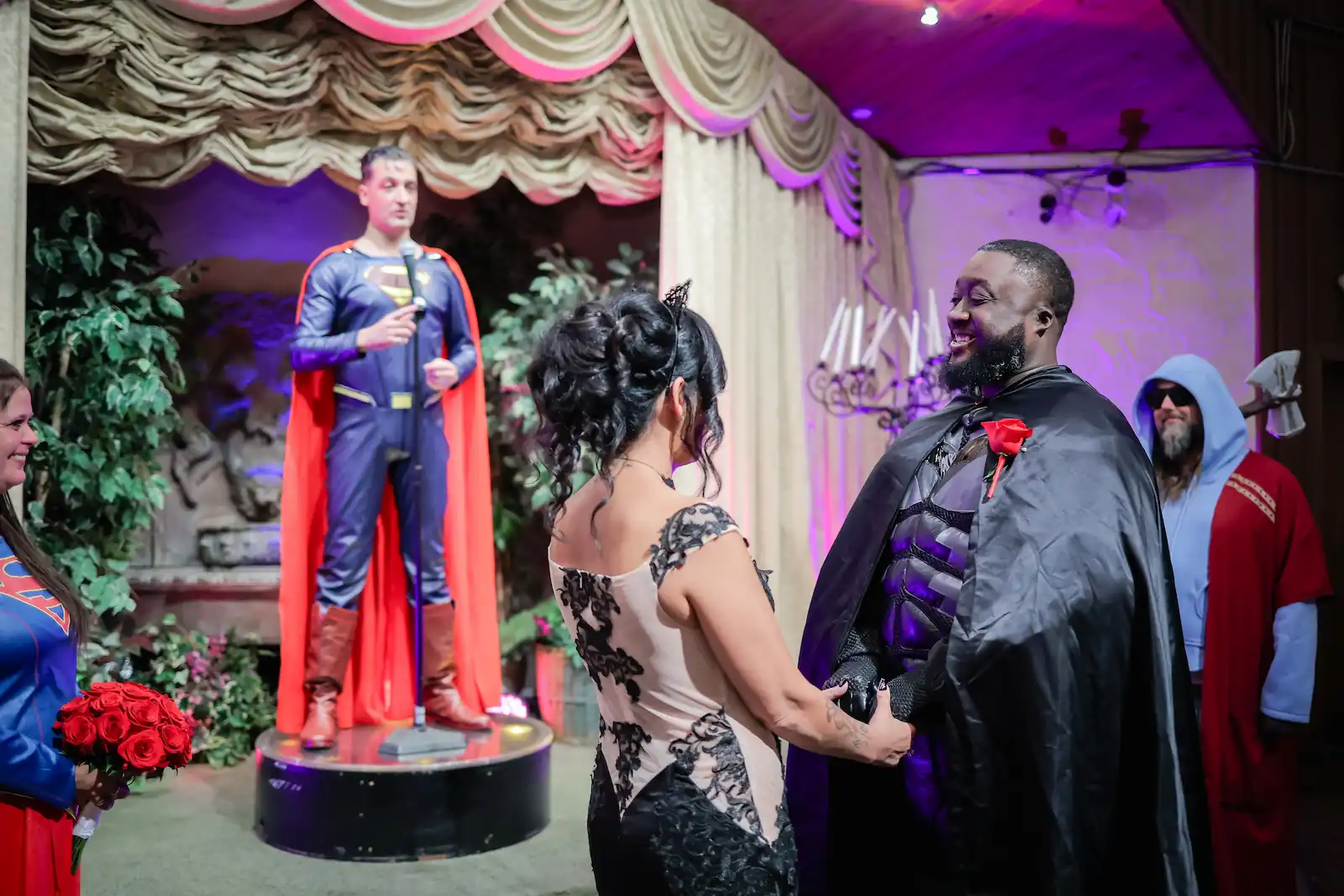 Couple in superhero cosplay exchanging vows with Superman impersonator officiating at a Las Vegas wedding chapel
