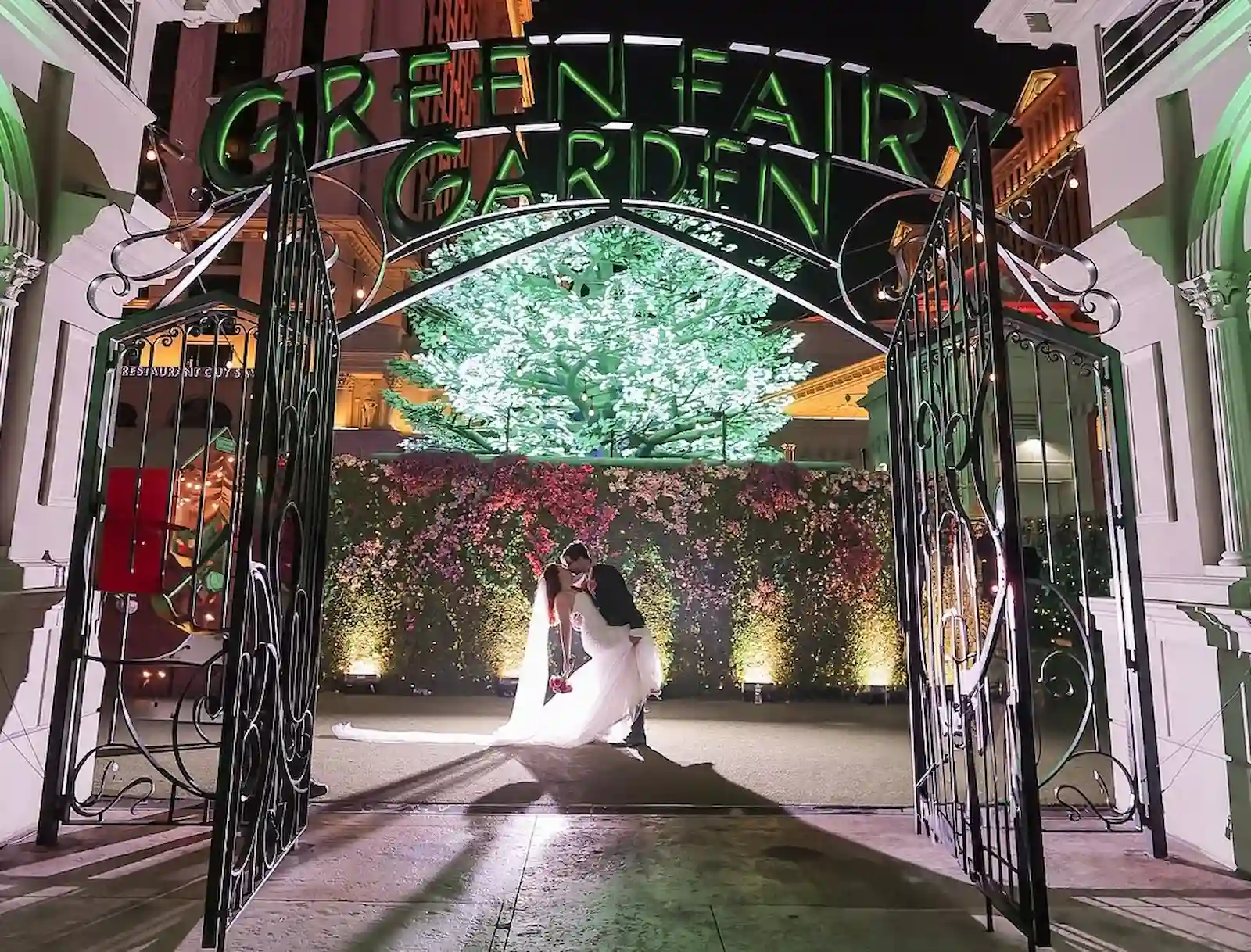 Bride and groom sharing a dip kiss at the Green Fairy Garden in Las Vegas at night